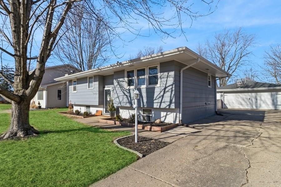 view of front of property with a garage, an outbuilding, and a front lawn