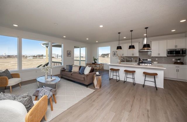 living area featuring baseboards, light wood-type flooring, and recessed lighting