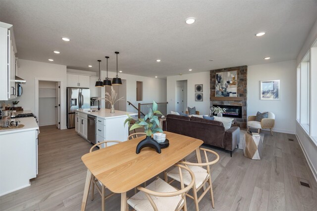 dining space featuring a fireplace, sink, light hardwood / wood-style floors, and a textured ceiling