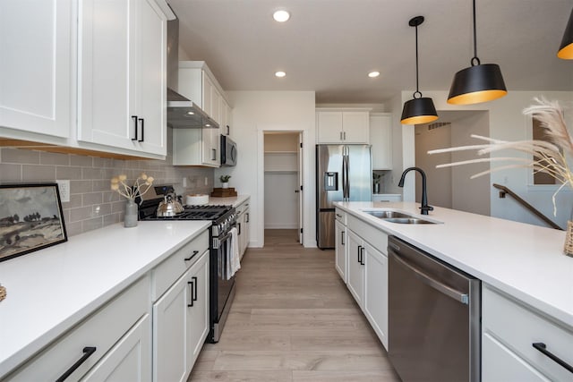 kitchen with white cabinets, appliances with stainless steel finishes, a sink, light countertops, and backsplash