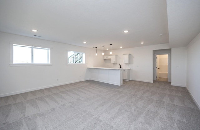 unfurnished living room featuring sink and light carpet