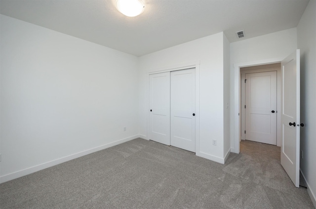 unfurnished bedroom featuring light colored carpet and a closet