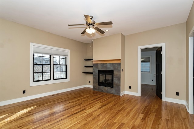 unfurnished living room featuring ceiling fan, wood-type flooring, and a fireplace