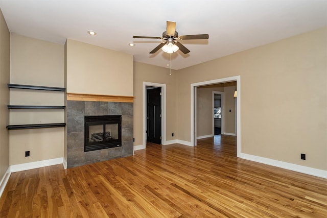 unfurnished living room with hardwood / wood-style floors, a tile fireplace, and ceiling fan