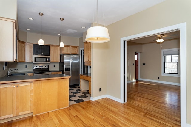 kitchen featuring appliances with stainless steel finishes, pendant lighting, sink, kitchen peninsula, and light hardwood / wood-style flooring