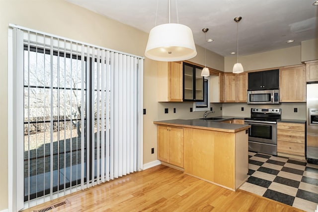 kitchen with pendant lighting, light brown cabinetry, sink, kitchen peninsula, and stainless steel appliances