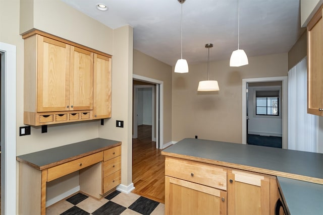 kitchen with hanging light fixtures, built in desk, and light brown cabinetry