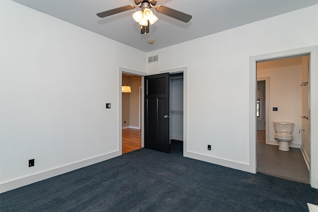 unfurnished bedroom with connected bathroom, ceiling fan, and dark colored carpet