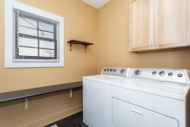 washroom with dark tile patterned flooring, cabinets, and washing machine and clothes dryer