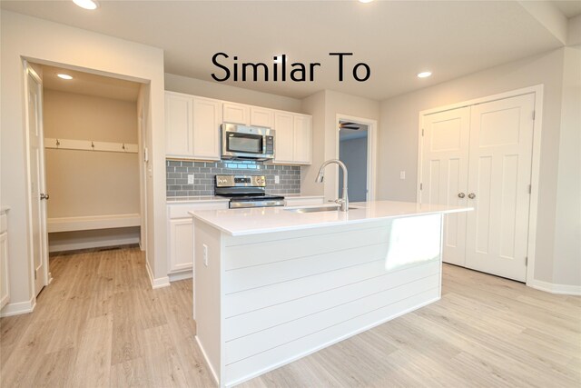 kitchen featuring white cabinetry, appliances with stainless steel finishes, sink, and a kitchen island with sink