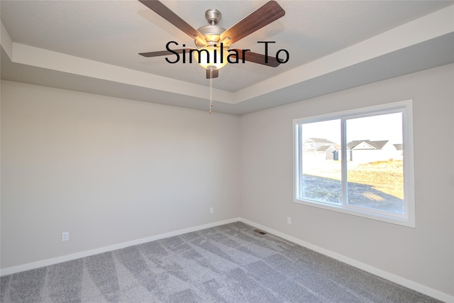 empty room featuring a textured ceiling, a raised ceiling, ceiling fan, and carpet