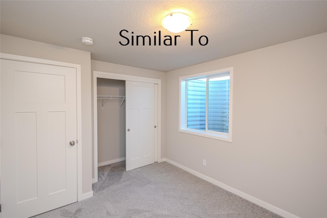 unfurnished bedroom featuring a closet, light carpet, and a textured ceiling