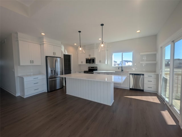 kitchen featuring sink, decorative light fixtures, a kitchen island, stainless steel appliances, and white cabinets