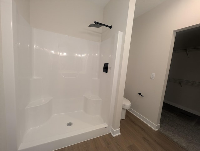 bathroom featuring hardwood / wood-style flooring, toilet, and walk in shower