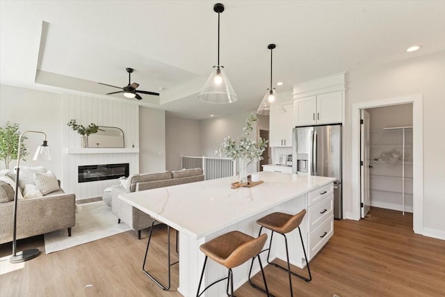 1902 16th Cir SE, Altoona, IA 50009 - kitchen featuring wood finished floors, stainless steel refrigerator with ice dispenser, white cabinetry, a breakfast bar area, and recessed lighting