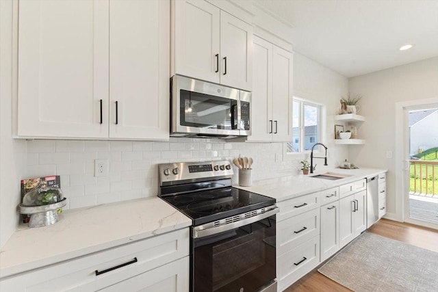 1902 16th Cir SE, Altoona, IA 50009 - kitchen with stainless steel appliances, open shelves, white cabinets, light wood-style floors, and backsplash