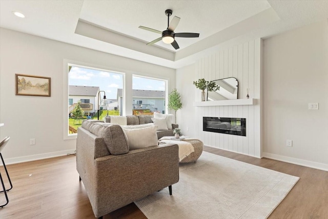 1902 16th Cir SE, Altoona, IA 50009 - living room featuring wood finished floors, ceiling fan, a tray ceiling, a fireplace, and recessed lighting