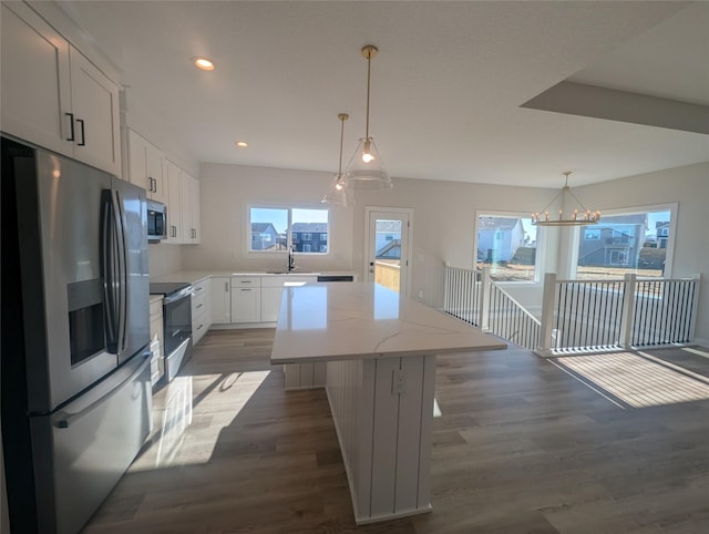 kitchen featuring white cabinetry, hanging light fixtures, a kitchen island, and appliances with stainless steel finishes