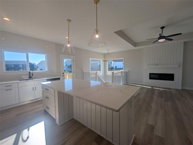 kitchen with decorative light fixtures, a wealth of natural light, white cabinets, and a kitchen island