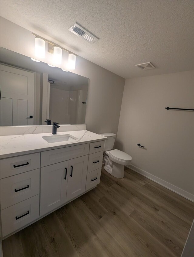 bathroom featuring vanity, wood-type flooring, a textured ceiling, and toilet