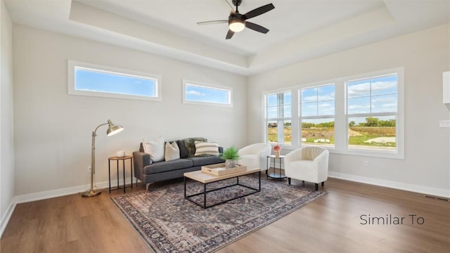 sitting room with ceiling fan, wood-type flooring, and a raised ceiling