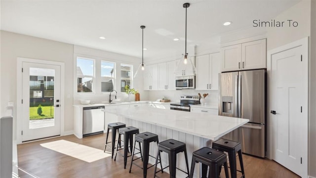 kitchen with pendant lighting, sink, white cabinets, a center island, and stainless steel appliances