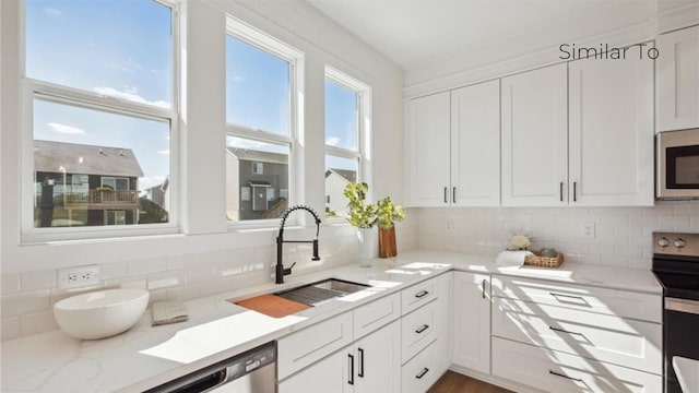 kitchen featuring sink, stainless steel appliances, light stone counters, white cabinets, and decorative backsplash