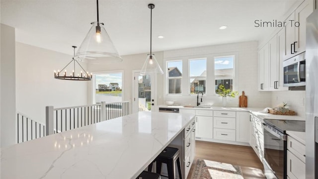 kitchen featuring sink, hanging light fixtures, plenty of natural light, stainless steel appliances, and white cabinets