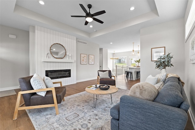 1632 20th Ave SE, Altoona, IA 50009 - living room with a tray ceiling, a ceiling fan, a large fireplace, wood finished floors, and recessed lighting