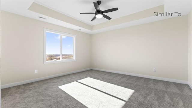 unfurnished room with a tray ceiling, ceiling fan, and carpet