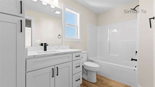 full bathroom featuring washtub / shower combination, wood-type flooring, toilet, and vanity