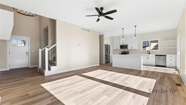 kitchen featuring sink, decorative light fixtures, a center island, appliances with stainless steel finishes, and white cabinets