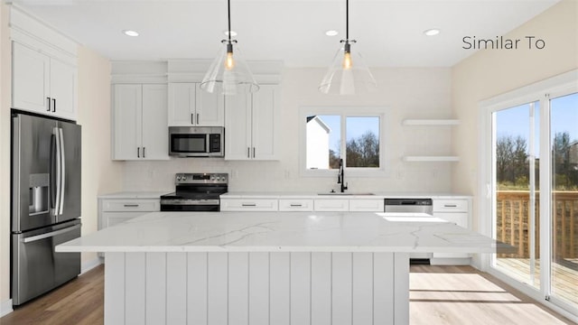 kitchen featuring appliances with stainless steel finishes, light stone countertops, sink, and a kitchen island