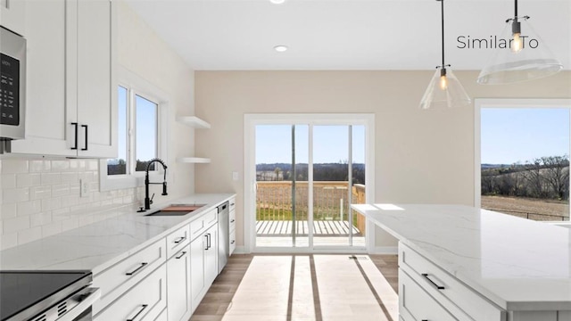 kitchen featuring sink, white cabinetry, decorative light fixtures, light stone countertops, and backsplash