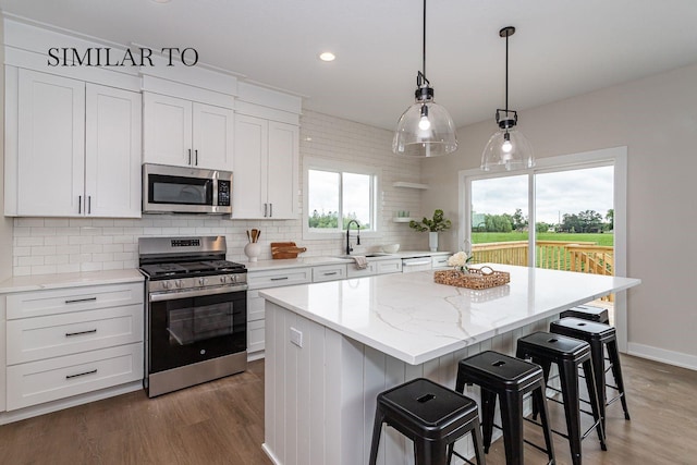 kitchen featuring stainless steel appliances, white cabinetry, a kitchen island, and sink