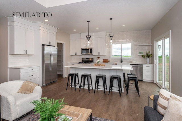 kitchen featuring backsplash, hanging light fixtures, stainless steel appliances, a center island, and white cabinets