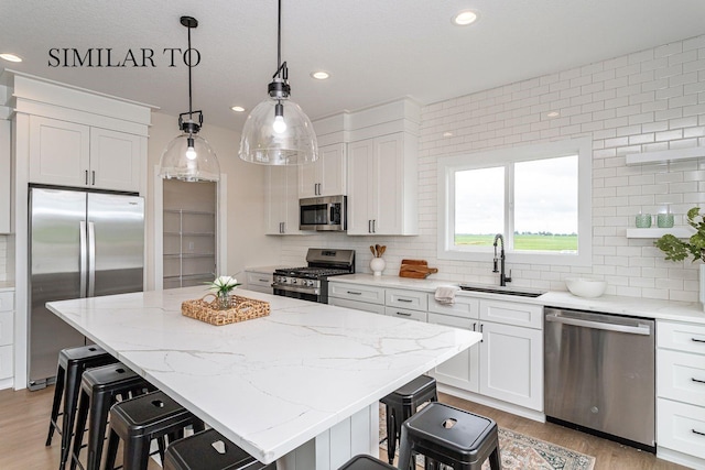 kitchen featuring a kitchen island, white cabinetry, appliances with stainless steel finishes, and sink