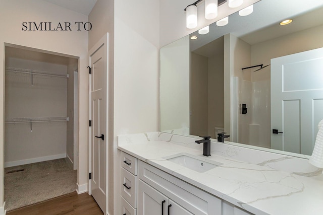 bathroom with hardwood / wood-style flooring, vanity, and a shower