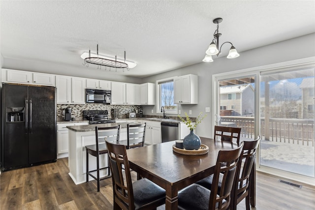 dining room with sink, a notable chandelier, dark wood-type flooring, and a textured ceiling