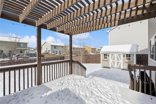 snow covered deck featuring a storage unit and a pergola