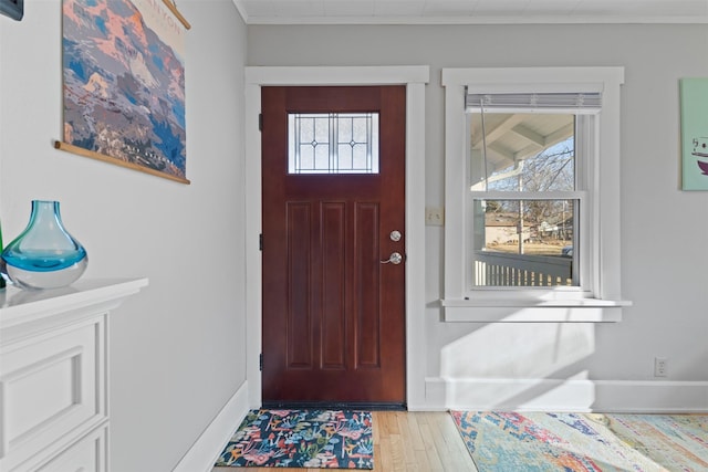 entryway featuring a wealth of natural light, ornamental molding, and light wood-type flooring