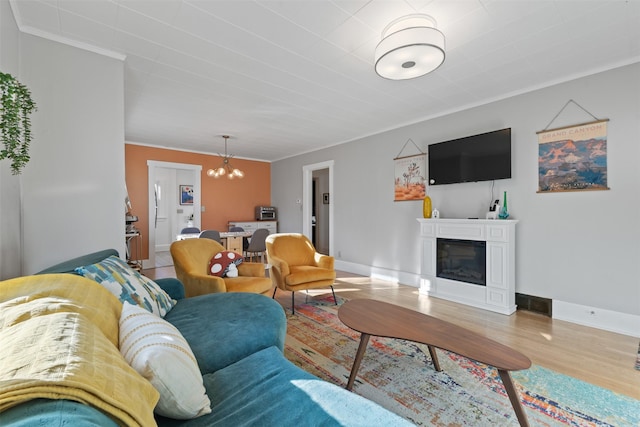 living room with crown molding, a notable chandelier, and light wood-type flooring