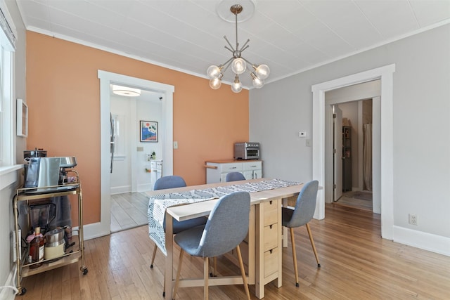 dining area with crown molding, light wood-type flooring, and a chandelier