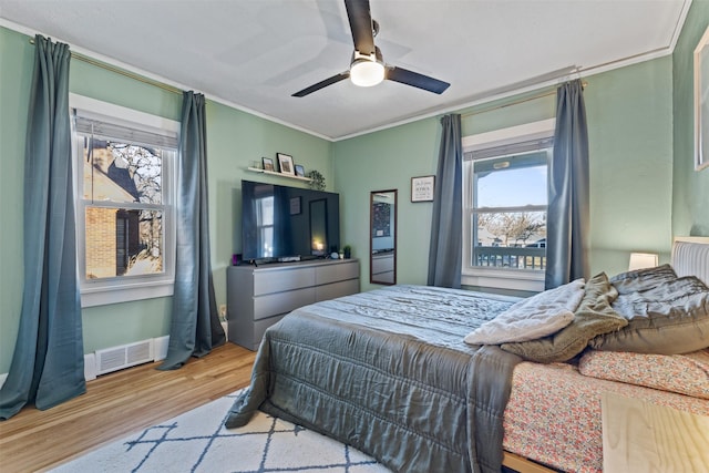 bedroom with crown molding, light hardwood / wood-style floors, and ceiling fan