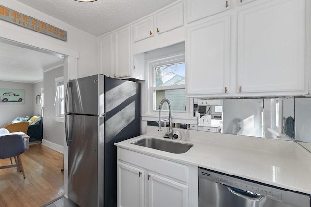 kitchen featuring appliances with stainless steel finishes, sink, a textured ceiling, and white cabinets