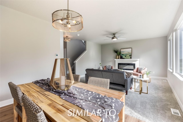 dining space featuring ceiling fan with notable chandelier