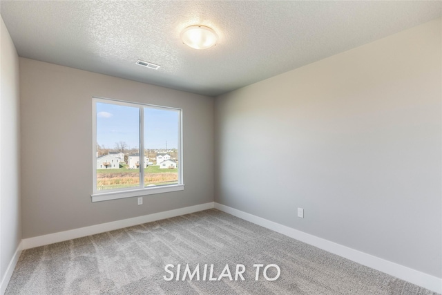 spare room with a textured ceiling and carpet