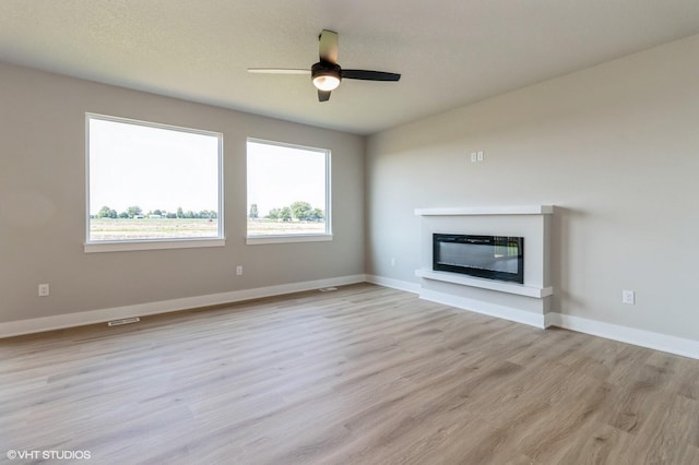 319 41st St SW, Altoona, IA 50009 - unfurnished living room with light wood finished floors, a glass covered fireplace, and ceiling fan