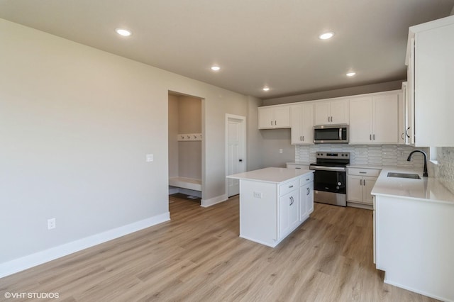 319 41st St SW, Altoona, IA 50009 - kitchen with stainless steel appliances, light wood finished floors, a center island, decorative backsplash, and light countertops