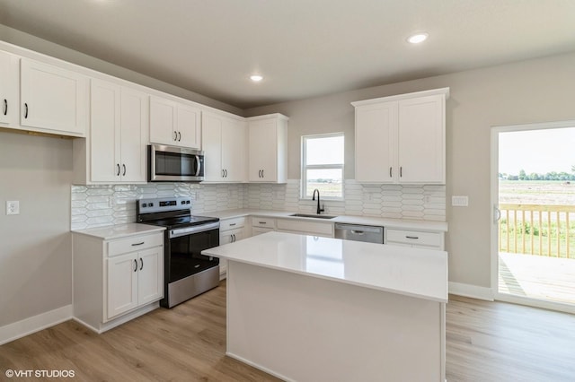 319 41st St SW, Altoona, IA 50009 - kitchen featuring appliances with stainless steel finishes, light wood-style floors, a kitchen island, white cabinetry, and decorative backsplash